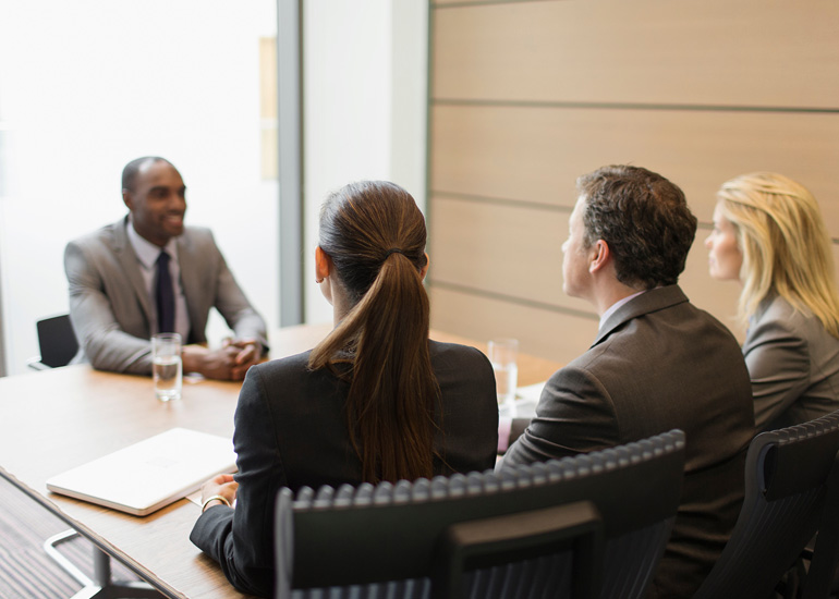 Business people interviewing businessman in conference room